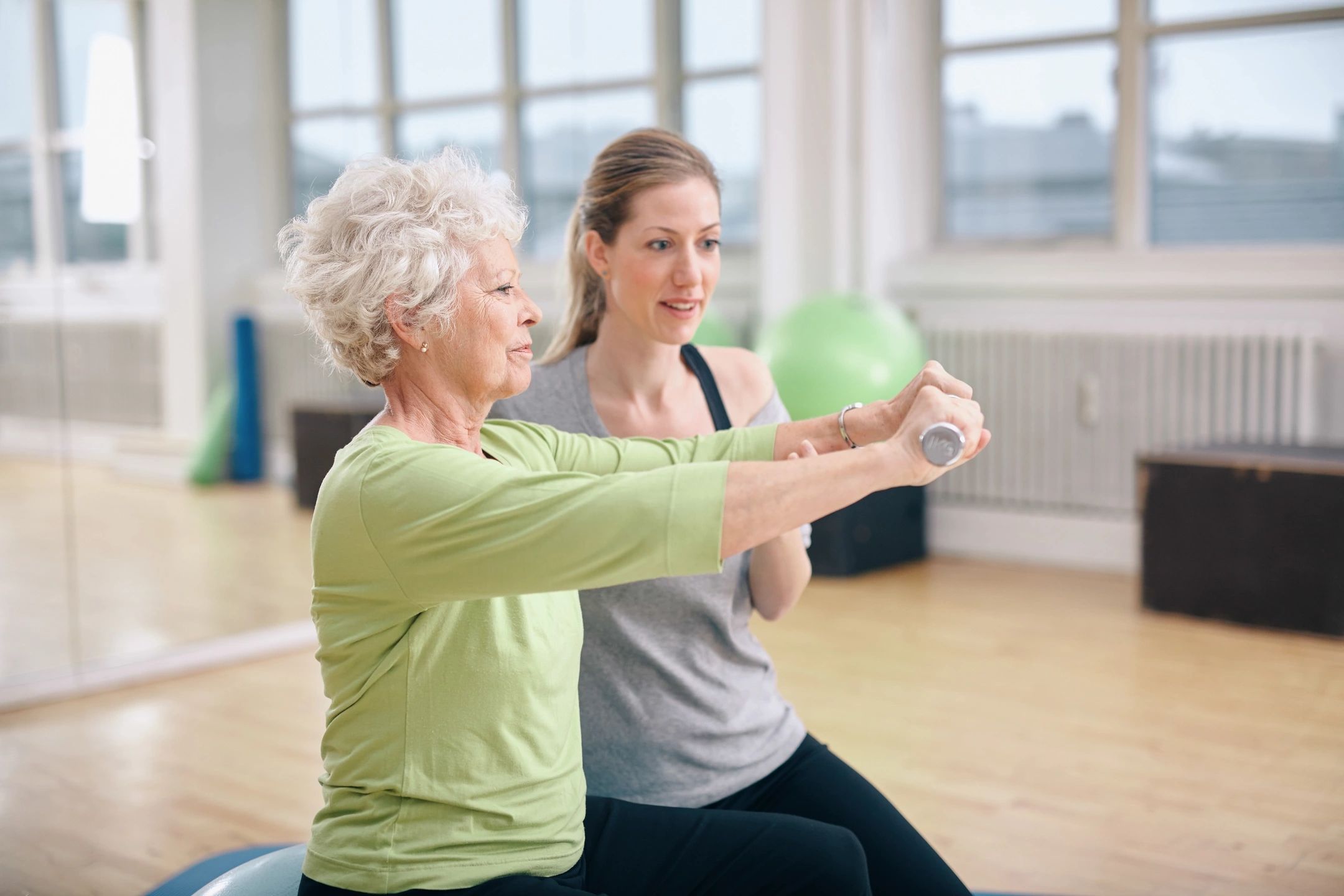 Sunshine Strength and Balance Senior Fitness Program in Bradenton, FL. Image of an elderly woman being assisted by a physical therapist.