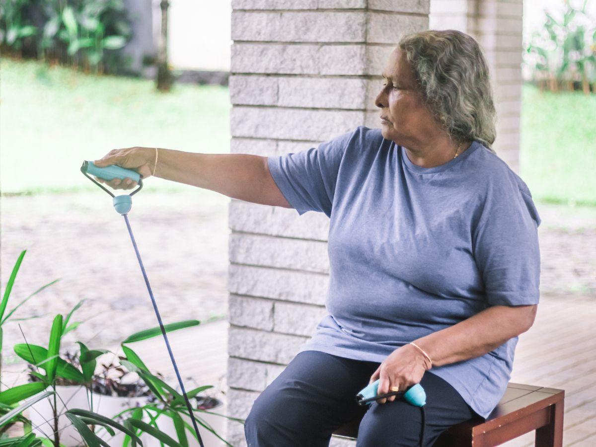 Older woman sitting on a bench outdoors, performing a gentle functional exercise in Sarasota.